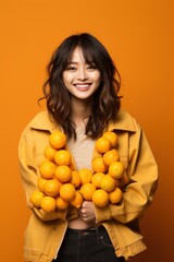 Obraz premium Cheerful Asian woman holding a bunch of oranges