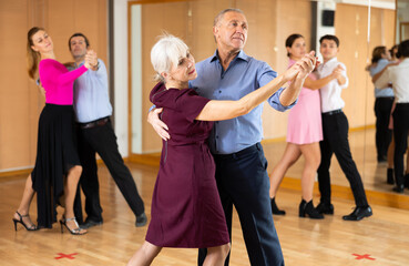 Fototapeta premium active elderly people attend dance lessons for amateurs and learn to dance waltz in their free time