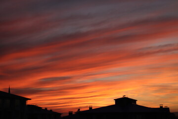 A dramatic sunset with radiant hues of orange and red streaking across the sky, silhouetting the...