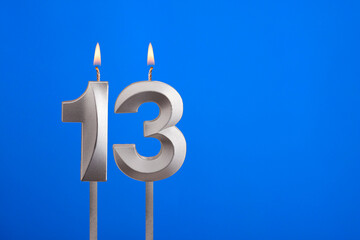 Birthday number 13 - Candle lit on blue background