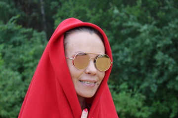 A woman in sunglasses and a red hood. Portrait in nature.