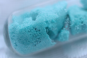 Turquoise salt nickel sulfate in the form of crystal hydrate in a test tube.
