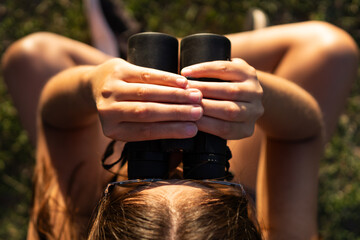Close-up shot taken from above of the head of an unrecognizable woman looking through binoculars in...