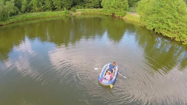 Four kids boys and little girls play on inflated boat on pond
