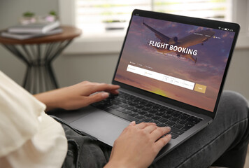 Fototapeta na wymiar Woman using laptop to book flight at home, closeup