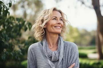 Portrait of a happy mature woman smiling in the park at autumn - obrazy, fototapety, plakaty