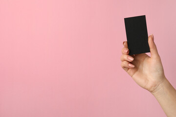 Woman with blank black business card on pink background, closeup. Mockup for design