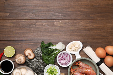 Cooking delicious ramen soup. Different ingredients on wooden table, flat lay. Space for text