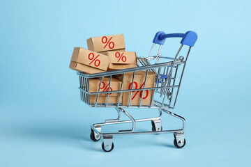 Discount offer. Boxes with percent signs in mini shopping cart on light blue background