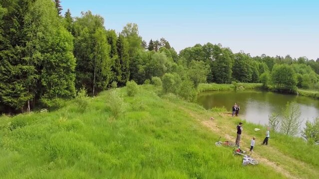 Parents with kids stand on shore of pond in Borovsk
