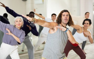 Positive man practicing active dancing during group training in dance studio. Сoncept of healthy...