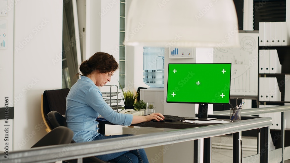 Poster empty desk with greenscreen layout on computer in coworking space with people solving business opera