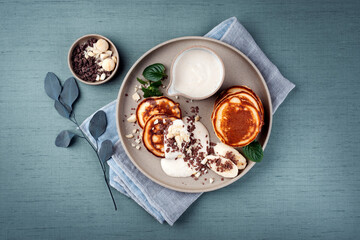 Traditional American Pancakes with banana honey cream, macadamia nuts and chocolate crumbles served as top view on a Nordic design plate - obrazy, fototapety, plakaty