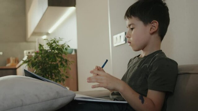 Little boy writing homework, learing alphabet looking very happy. Education, family and homework concept.