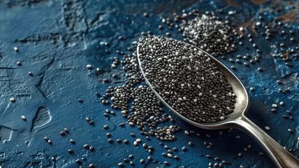 Fotobehang Spoonful of chia seeds on a textured blue surface © Artyom