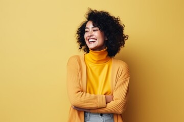 Portrait of a happy african american woman laughing over yellow background