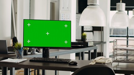 Empty office with greenscreen on computer display, marketing agency open floor plan. Coworking space with monitor running isolated mockup template, blank chromakey copyspace at desk.