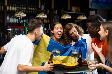 Joyful friends with the flag of Sweden celebrating the victory of their favorite team in a beer bar