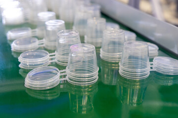 Production of plastic products from PP polypropylene. Conveyor belt with rows of round transparent containers with lids. Production line for molding food packaging made of transparent plastic