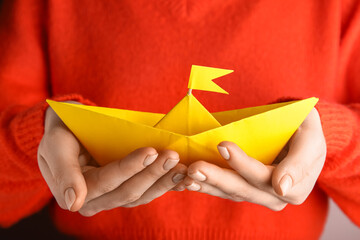 Woman holding yellow origami boat, closeup