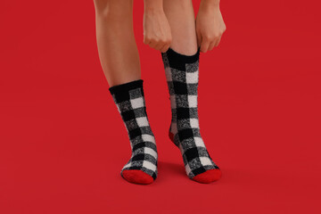 Legs of young woman in warm socks on red background