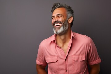 Portrait of a handsome mature man with grey hair and beard laughing against grey background