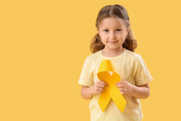 Cute little girl with yellow ribbon on color background. Childhood cancer awareness concept