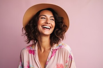 Portrait of a smiling young woman in summer hat over pink background