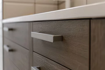 Deurstickers A detailed view of a modern bathroom cabinet with textured wood finish and a sleek metal handle, exemplifying contemporary interior design. © Ярослава Малашкевич
