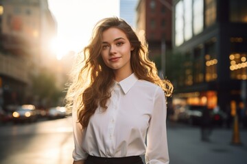 Fototapeta premium A sophisticated woman in a chic scallop-edged skirt and crisp button-up shirt, standing confidently in a bustling city street, with the sun setting behind the towering skyscrapers