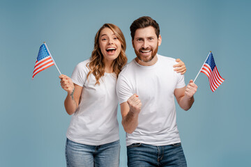 Overjoyed man and woman holding American flags isolated on blue background. Voting, Election day...