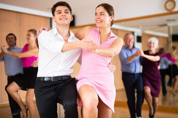 Active young pair practicing Latino dance in training hall during dancing-classes. Pairs training ballroom dance