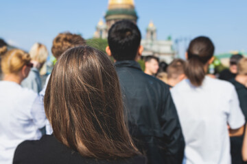 Group of students and school pupils on outdoor excursion tour in the city streets with guide, a docent with a tourist adult visitors, school field trip, urban tour in the summer sunny day