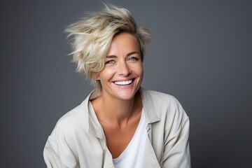 Portrait of a smiling woman with blond hair against a grey background
