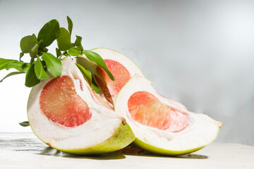 Closeup front view, sliced ​​red pomelo fruit, on a table on a white background in the studio