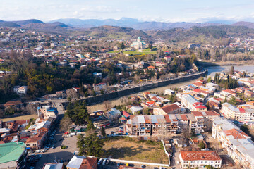 Fototapeta na wymiar View from drone of historical districts of old Georgian city of Kutaisi on both sides of Rioni river with rebuilt building of Cathedral 