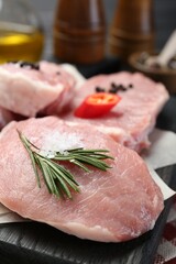 Pieces of raw pork meat with chili pepper and spices on board, closeup