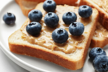 Delicious toasts with peanut butter and blueberries on table, closeup