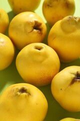 Tasty ripe quinces on light green background, closeup