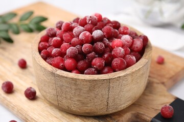 Frozen red cranberries in bowl on table, closeup