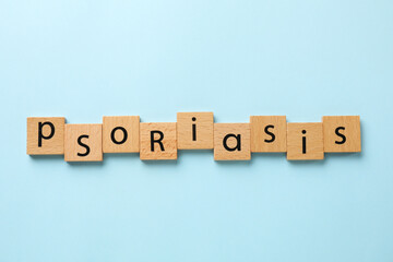 Word Psoriasis made of wooden squares with letters on light blue background, top view
