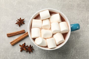 Tasty hot chocolate with marshmallows and spices on light grey table, flat lay