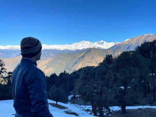a person looking out over a valley with snowy mountains in the background