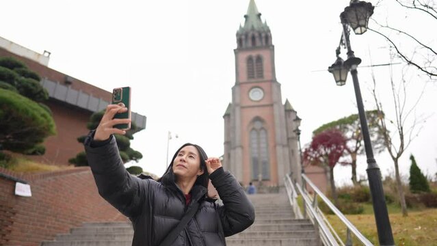 韓国のソウルの明洞の寒い冬に教会を訪れるロングヘアーの30代の韓国人男性のスローモーション映像 Slow-motion video of a long-haired Korean man in his 30s visiting a church in the cold winter in Myeong-dong, Seoul, South Korea