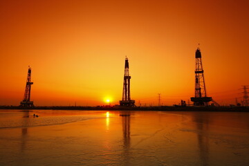 Obraz premium Sunset of oil drilling rig in the sea