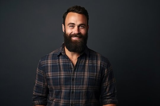 Portrait of a handsome man with a beard in a plaid shirt on a dark background