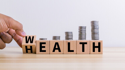 Hand flip wooden cube with word wealth to health with coins stack step up growing growth value. Investment in life insurance and healthcare concept