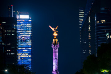 Illuminated view of night Mexico city with glowing The Angel of Independence statue placed among tall skyscrapers in evening Mexico city © Itza