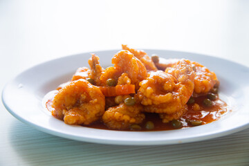 fried shrimp with sweet and sour seasoning served on a white plate