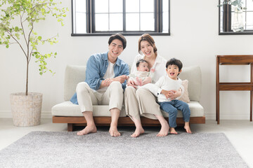 Also in the main visual! A friendly Asian (Japanese) family of four looking at the camera in a newly built-like room in bright sunlight Wide angle